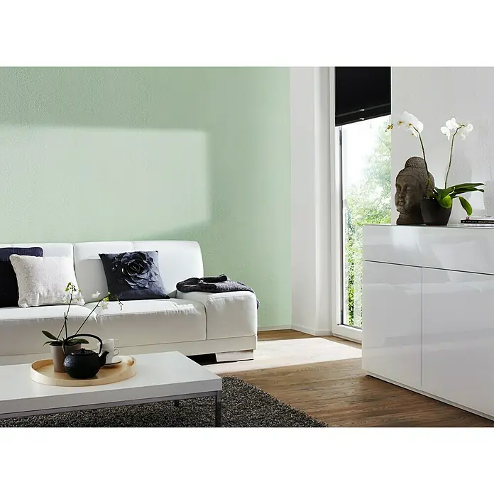 Knauf Putz-Abtönfarbe Compact Color - Jade, 6 g - Wohnzimmer mit weißem Sofa, Couchtisch und einer Kommode dekoriert mit einer Buddha-Statue und Orchideen.