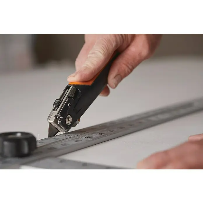Fiskars CarbonMax Cúter Placas de yeso - Tipo de cuchilla: Cuchilla trapezoidal, 3 posiciones de la cuchilla, Negro/Naranja - Producto en uso