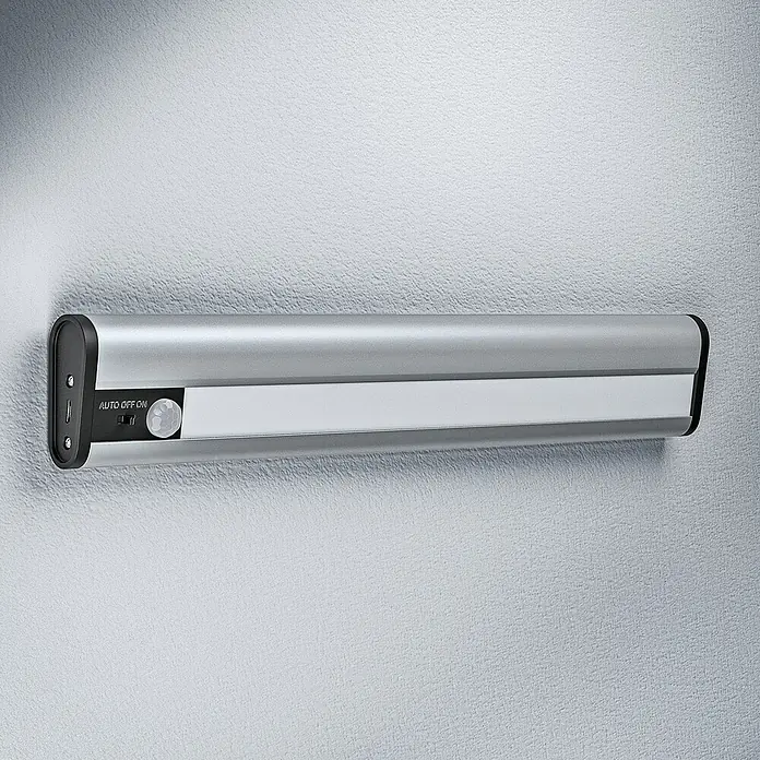 Ledvance Lámpara LED bajo mueble - 1,4 W, Blanco frío, Largo: 300 mm, Modo de funcionamiento: Funciona con pilas - Luz LED plateada con sensor de movimiento montada en una pared blanca. Ideal para armarios y rincones oscuros.