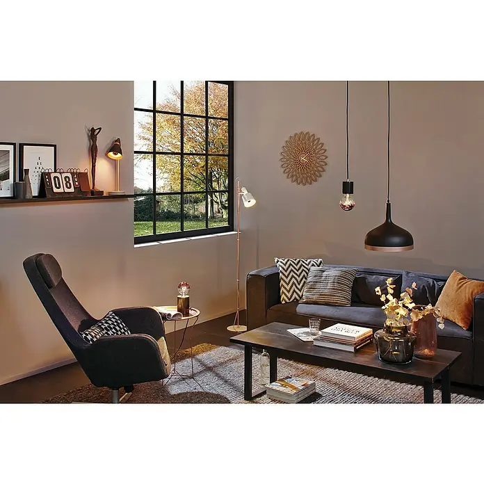 Paulmann Neordic Pendelleuchte Embla - Höhe: 110 cm, Schwarz/Kupfer - Elegantes Wohnzimmer mit dunklem Sofa, Sessel und stilvollen Lampen, die eine warme Atmosphäre schaffen. Holzdetails und Textilien runden das Design ab.