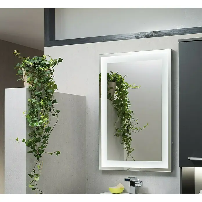Camargue Stella LED-Lichtspiegel - 80 x 60 cm, Mit Kippschalter, Mit eckigen Kanten - Ein beleuchteter Badezimmerspiegel hängt über einem Waschbecken, neben einem grauen Schrank. Eine Topfpflanze auf der linken Seite fügt einen Farbtupfer hinzu.