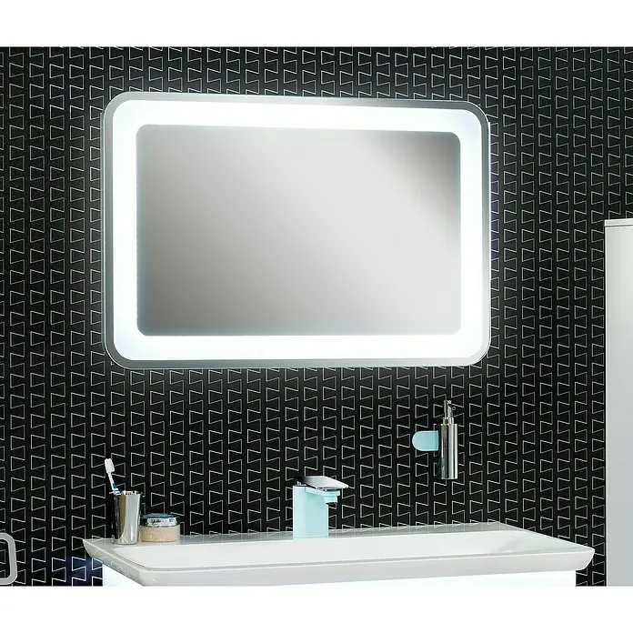Camargue Stella LED-Lichtspiegel - 90 x 60 cm, Mit Kippschalter, Mit abgerundeten Kanten - Ein rechteckiger, beleuchteter Spiegel hängt über einem weißen Waschbecken vor einer gemusterten Wand.