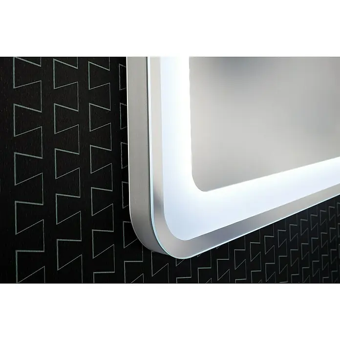 Camargue Stella LED-Lichtspiegel - 100 x 70 cm, Stufenlose Lichttemperaturverstellung, Mit abgerundeten Kanten - Nahaufnahme eines beleuchteten Spiegels an einer Wand mit einem modernen Zickzackmuster, das die schlanken Linien und das sanfte Licht des Spiegels hervorhebt.