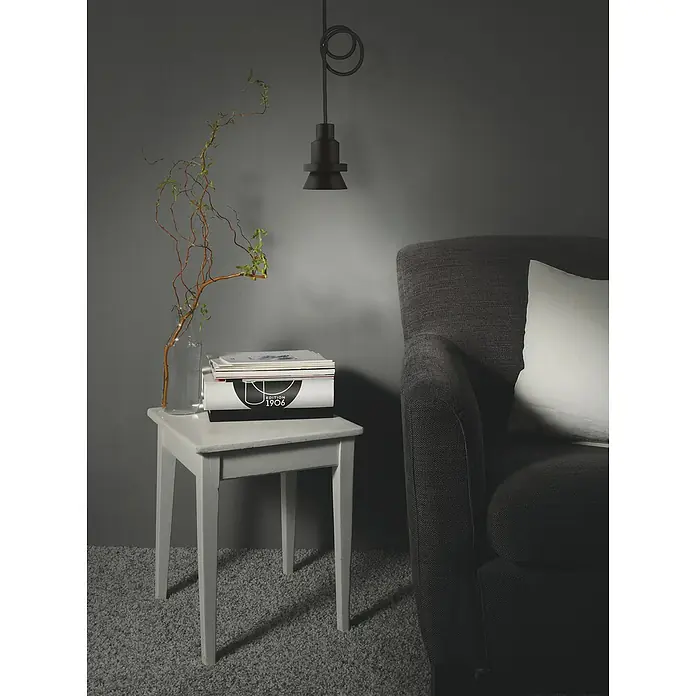 Ledvance LED-Pendelleuchte rund - Ø x H: 68 mm x 208,4 cm, Schwarz - Nahaufnahme einer Lampe, einem Tisch mit Vase und einem Magazinstapel, neben einem grauen Sessel mit weißem Kissen.