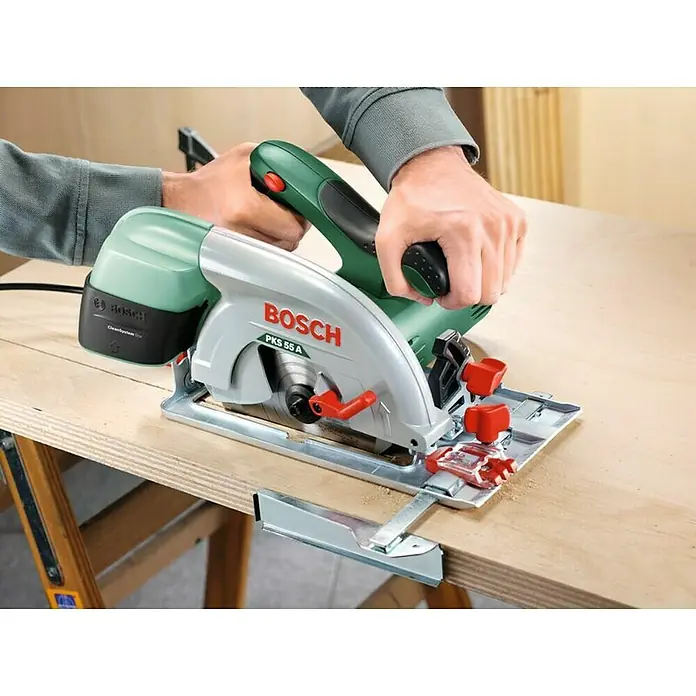Bosch Handkreissäge PKS 55 A - 1.200 W, Ø 160 mm, 5.600 U/min - Aufsicht auf eine Bosch PKS 55 A Kreissäge, die auf einem Holztisch steht und von zwei Händen bedient wird, um einen sauberen Schnitt zu gewährleisten.