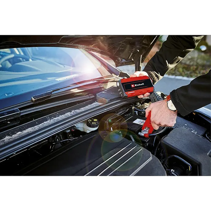 Einhell Kit de arranque CE-JS 12 - 12 V, Corriente máx. de carga: 400 A - Un hombre arranca la batería de un coche con un arrancador Einhell. El dispositivo rojo es compacto y fácil de usar.