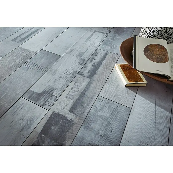 MyStyle MyDream Laminado AC6-33 Pino Native Urban - 1.285 x 192 x 14 mm, Efecto madera campestre - Un primer plano de un suelo con diseño de madera con libros encima, transmitiendo un ambiente acogedor.
