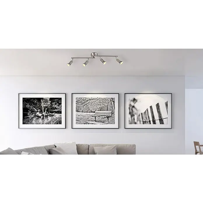 LED-Deckenstrahler Matrix - 12 W, Warmweiß - Eine moderne Deckenleuchte mit vier Strahlern beleuchtet stilvoll gerahmte Schwarz-Weiß-Fotografien in einem Wohnraum.