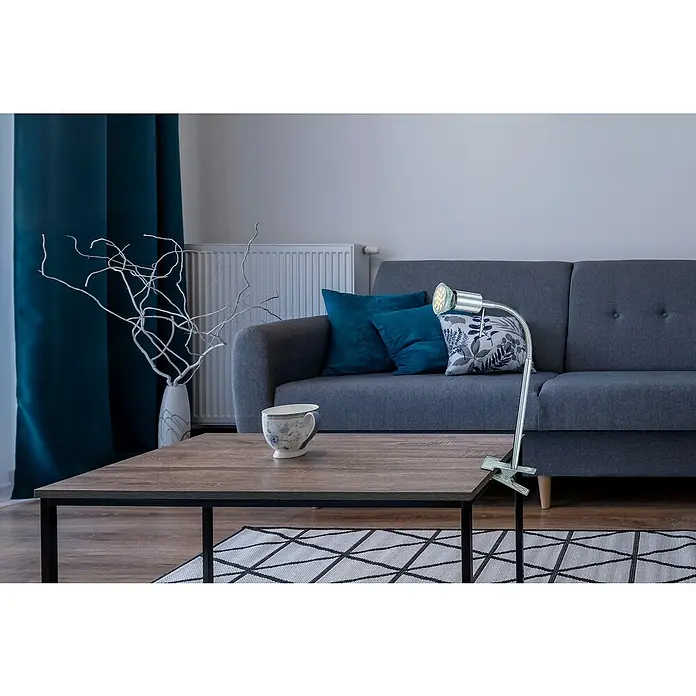 Globo LED-Klemmleuchte - 1-flammig, 3 W, Nickel matt - Nahaufnahme einer modernen Wohnzimmerszene mit einem grauen Sofa, blauen Kissen und einer Clip-Tischleuchte auf einem Holztisch.