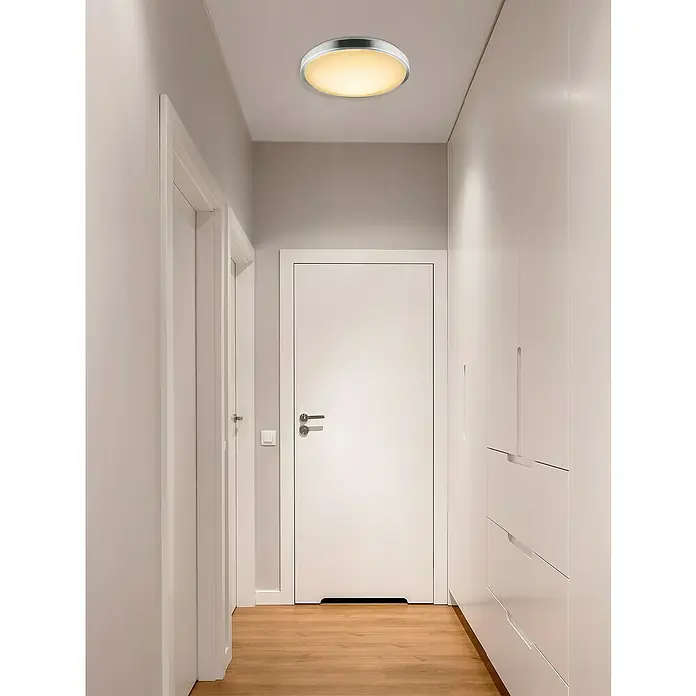 Lavida Led-plafondlamp, rond Forli - 18 W, Ø x h: 350 mm x 10 cm, Wit - Een moderne plafondlamp met een ronde, zilveren rand en een zacht, gelig licht in een gang.