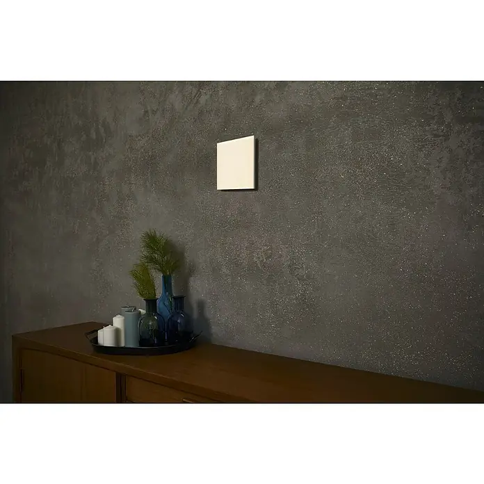 Ledvance Smart+ WiFi LED-Panel Planon Frameless - 36 W, L x B x H: 30 x 30 x 6,9 cm, Weiß, RGBW - Elegantes Arrangement auf einer Holzkommode mit Kerzen, blauen Vasen und Grünpflanzen vor einer stilvollen Wand mit quadratischem Spiegel.