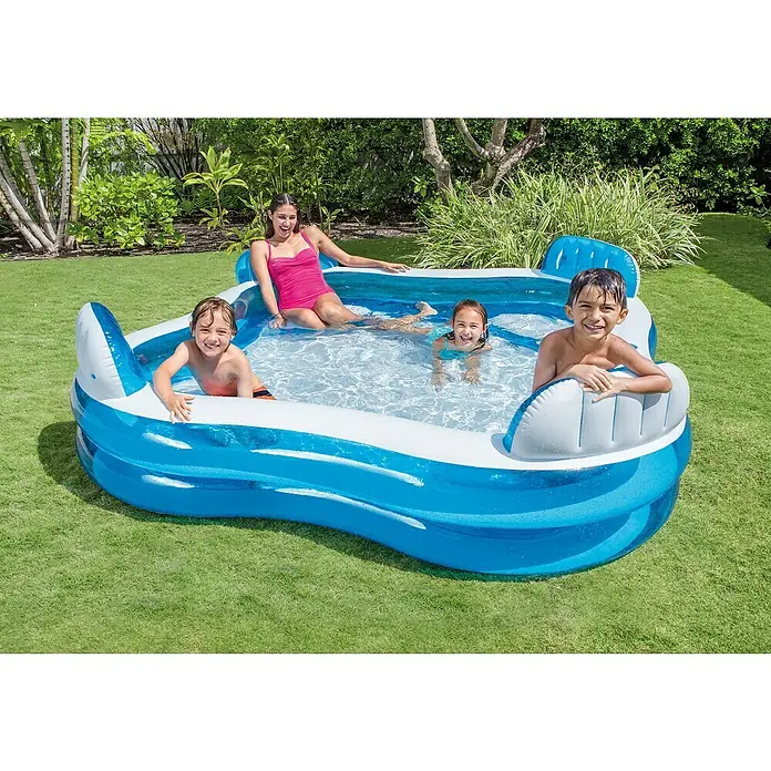 Intex Piscina exterior Family Lounge - 229 x 229 x 66 cm, 0,88 m³ - Una piscina azul Intex con cuatro personas en el jardín. La piscina cuenta con áreas de estar integradas para mayor comodidad y relajación.