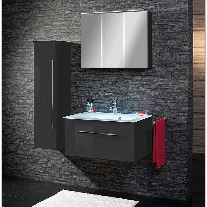 Camargue Stella LED-Spiegelschrank - B x H: 80 x 68,4 cm, Mit Beleuchtung, Spanplatte, Grafit - Ein modernes Badezimmer-Set in Grau mit Waschbeckenunterschrank, Spiegelschrank und Hochschrank vor einer dunklen Steinwand.