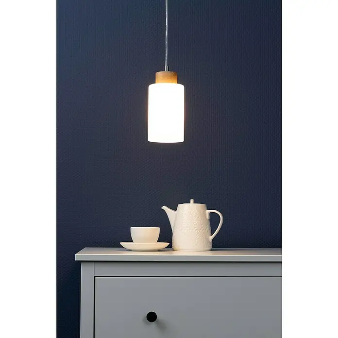 Spotlight Pendelleuchte rund Bosco - 60 W, Ø x H: 100 mm x 110 cm, Geölte Eiche, E27 - Eine moderne Hängelampe mit einem Schirm aus mattiertem Glas und einem Holzaufsatz, die über einem grauen Tisch mit Teekanne und Tasse hängt.