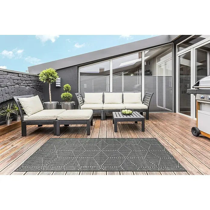 Outdoor-Teppich Planus - Dunkelgrau, 170 x 120 cm, 100 % Polypropylen - Grauer Outdoor-Teppich mit geometrischem Muster auf einer Holzterrasse mit Gartenmöbeln und Grill.