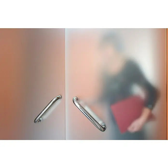 Lámina adhesiva Zarame - Transparente, Con adherencia estática - Vista a través de una puerta de vidrio esmerilado con manijas cromadas de una persona con una carpeta roja. Las manijas son de cromo y brillantes.