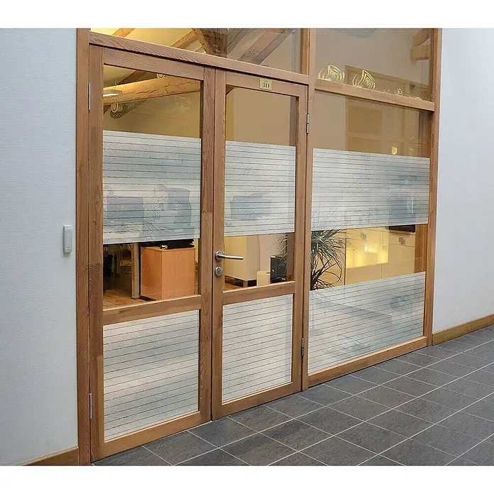 Protección de vinilo al corte Mayo - Ancho: 46 cm, Transparente - Una puerta de madera con paneles de vidrio y franjas horizontales, que ofrece una vista a un espacio de oficina con vigas de madera y muebles.