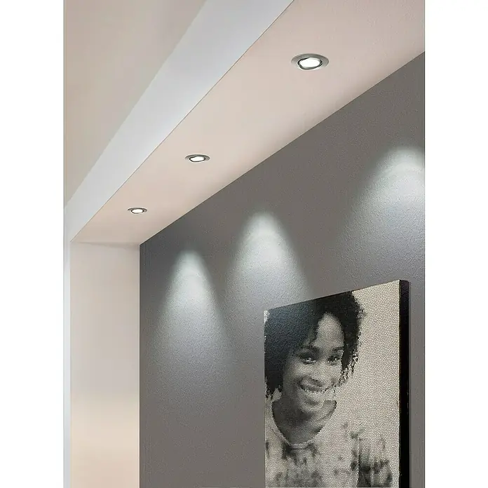 Eglo LED-Einbauleuchte Pineda - 6 W, L x B x H: 8,4 x 8,4 x 4 cm, Nickel matt, Warmweiß, Dimmbarkeit: Dimmbar - Moderne Deckeneinbaustrahler erhellen eine graue Wand mit einem Porträt. Die Leuchten sind elegant und unauffällig in die Decke integriert.