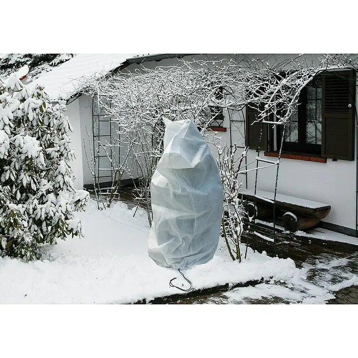 Floraworld Haubenvlies - 2 Stk., 100 x 150 cm, Geeignet für: Überwinterung - Eine Pflanze, die in einem Garten im Winter mit einem weißen Schutzvlies abgedeckt ist, um sie vor Frost zu schützen.