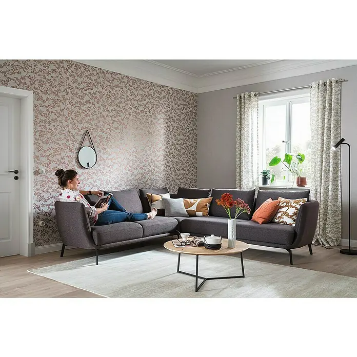 SCHÖNER WOHNEN-Kollektion New Spirit Vliestapete Struktur I - Grau/Gold, Floral, 10,05 x 0,53 m - Ein stilvolles Ecksofa in Grau mit dekorativen Kissen und einem passenden Couchtisch, ideal für ein gemütliches Wohnzimmer.
