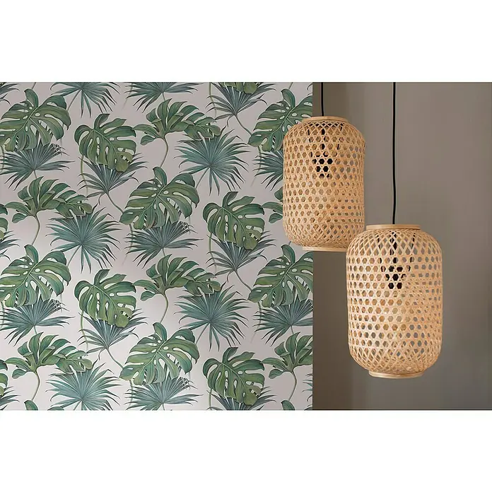 SCHÖNER WOHNEN-Kollektion New Spirit Vliestapete Fensterblatt - Grün/Weiß, Floral, 10,05 x 0,53 m - Zwei dekorative Hängelampen aus Korbgeflecht vor einer Wand mit tropischem Pflanzenmuster. Natürliche Beleuchtung für ein stilvolles Ambiente.